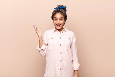 Genç afro kadın mutlu, şaşırmış ve neşeli, pozitif bir tavırla gülümseyen, bir çözüm ya da fikir gerçekleştiren