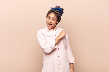 Genç afro kadın mutlu, pozitif ve başarılı hissediyor, meydan okumayla karşılaştığında motive oluyor veya iyi sonuçları kutluyor.