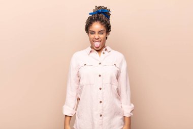 Genç afro kadın tiksinmiş ve rahatsız olmuş hissediyor. Dilini dışarı çıkarıyor. İğrenç ve iğrenç bir şeyden hoşlanmıyor.