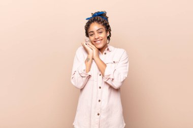 Genç afro kadın aşık ve sevimli görünüyor. Sevimli ve mutlu. Romantik bir şekilde gülümsüyor.