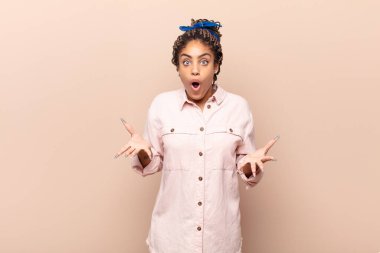 Genç afro kadın şok olmuş ve şaşırmış, endişeli ve panik içinde, stresli ve dehşete düşmüş bir bakışla