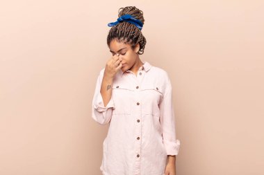 Genç afro kadın stresli, mutsuz ve hayal kırıklığına uğramış, alınına dokunmuş ve şiddetli baş ağrısı çeken.