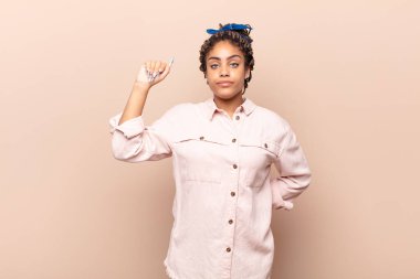 Genç afro kadın ciddi, güçlü ve asi hissediyor, yumruğunu kaldırıyor, protesto ediyor ya da devrim için savaşıyor.