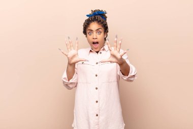 Genç afro kadın korku ve panik içinde geri çekilip çığlık atıyor ve bir kabusa tepki veriyor.