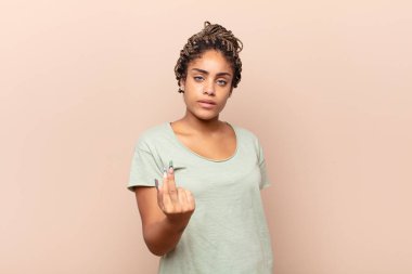 Genç afro kadın kızgın, sinirli, asi ve agresif hissediyor, orta parmağını hareket ettiriyor, karşı koyuyor.