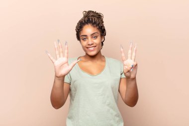 Genç afro kadın gülümsüyor ve arkadaş canlısı görünüyor, 8 ya da 8 numarayı gösteriyor, elleri önde, geriye doğru sayıyor.