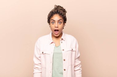 Genç afro kadın korkmuş ve şok olmuş hissediyor, ağzı açık şaşkınlık içinde.