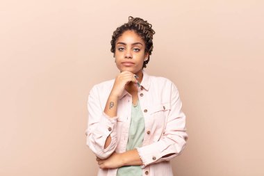 Genç afro kadın ciddi görünüyor, kafası karışık, kararsız ve düşünceli, seçenekler ya da seçimler arasında şüpheci