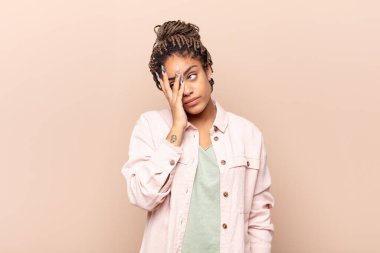 Genç afro kadın yorgun, sıkıcı ve sıkıcı bir görevin ardından sıkılmış, hayal kırıklığına uğramış ve uykulu hissediyor.