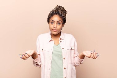 Genç afro kadın bilgisiz ve kafası karışık, hangi seçeneği seçeceğinden emin değil, merak ediyor.