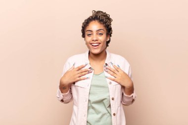 Genç afro kadın mutlu, şaşırmış, gururlu ve heyecanlı görünüyor.