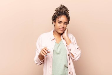 Genç afro kadın stresli, hayal kırıklığına uğramış ve yorgun hissediyordu. Endişeli ve sorunlu bir bakışla boynunu ovuyordu.