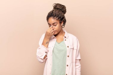 Genç afro kadın stresli, mutsuz ve hayal kırıklığına uğramış, alınına dokunmuş ve şiddetli baş ağrısı çeken.