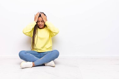 Genç afro kadın stresli ve endişeli, depresyonda ve hayal kırıklığına uğramış, iki elini de başa kaldırıyor.