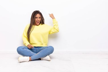 Genç afro kadın kendini mutlu, tatmin olmuş ve güçlü hissediyor, kaslı ve formda, spor salonundan sonra güçlü görünüyor.