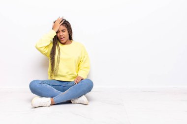young afro woman raising palm to forehead thinking oops, after making a stupid mistake or remembering, feeling dumb