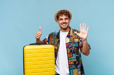 Genç adam gülümsüyor ve arkadaş canlısı görünüyor, altı ya da altıncı numarayı gösteriyor, eli önde, geriye doğru sayıyor. tatil kavramı