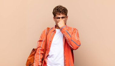 Delikanlı iğreniyor, pis ve nahoş bir kokuyu koklamamak için burnunu tutuyor. öğrenci konsepti