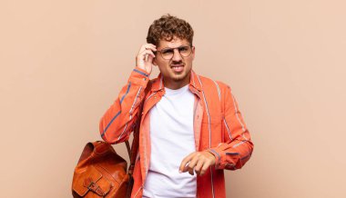 Genç adam stresli, hayal kırıklığına uğramış ve yorgun, endişeli ve sorunlu bir bakışla boynunu ovalıyor. öğrenci konsepti