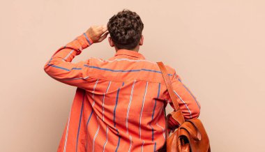 Genç adam bilgisiz ve kafası karışık, bir çözüm düşünüyor, eli kalçasında, diğeri kafasında, dikiz aynasında. öğrenci konsepti