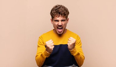 Delikanlı sinirli sinirli, sinirli bakışlar ve yumruklarla bağırıyor. Öfkeli hissediyor.