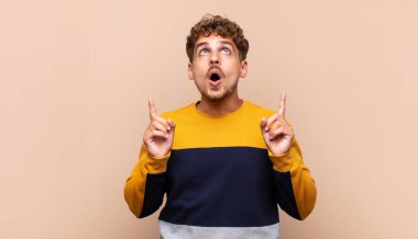 Delikanlı korkuyla ve ağzı açık bir şekilde şaşkın ve şaşkın bir bakışla yukarıya bakıyor.