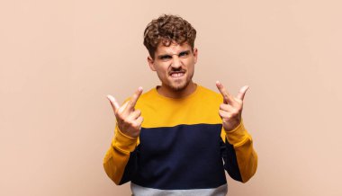 Genç adam kışkırtıcı, agresif ve müstehcen hissediyor. İsyankar bir tavırla orta parmağını hareket ettiriyor.