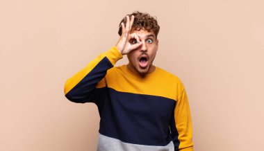 Genç adam şaşkın, şaşırmış ve şaşırmış hissediyor. Elinde şaşkın, inançsız bir bakışla gözlük tutuyor.