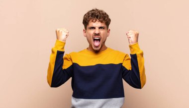 Genç adam öfkeli bir ifadeyle ya da yumruklarıyla başarıyı kutlarken agresif bir şekilde bağırıyor.