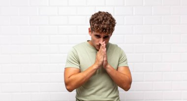 Genç adam endişeli, umutlu ve dindar, avuçlarına bastırılmış, af dileyen, sadakatle dua eden