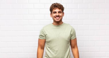 Genç adam mutlu ve şapşal görünüyor. Geniş, eğlenceli, deli gülüşü ve gözleri açık.