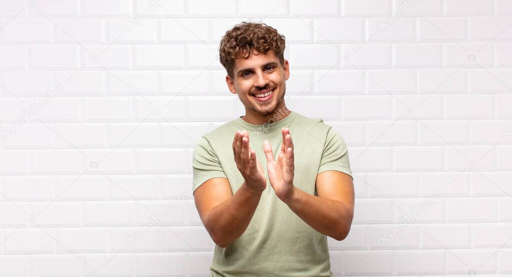 young man feeling happy and successful, smiling and clapping hands, saying congratulations with an applause