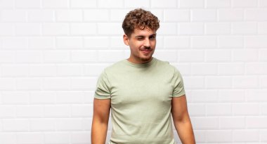 Genç adam mutlu ve arkadaş canlısı görünüyor, gülümsüyor ve sana olumlu bir tavırla göz kırpıyor.