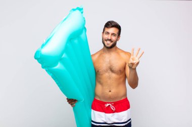 Genç adam gülümsüyor ve arkadaş canlısı görünüyor, iki ya da iki numarayı gösteriyor, eli önde, geri sayıyor. tatil kavramı