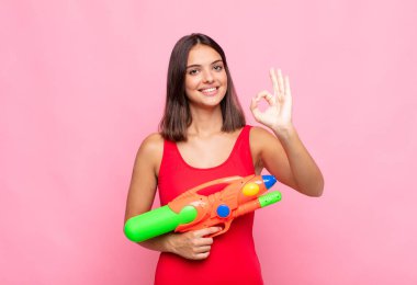 Genç, güzel bir kadın kendini mutlu, rahat ve tatmin olmuş hissediyor. İyi bir jestle onaylıyor, gülümsüyor. yaz konsepti