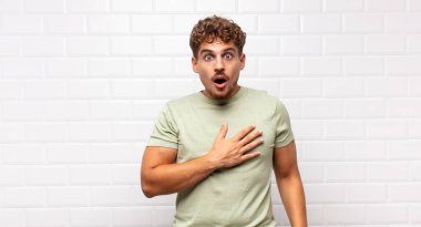 Genç adam şok olmuş ve şaşırmış hissediyor, gülümsüyor, el ele tutuşuyor, o olmaktan ya da minnettarlık göstermekten mutlu.