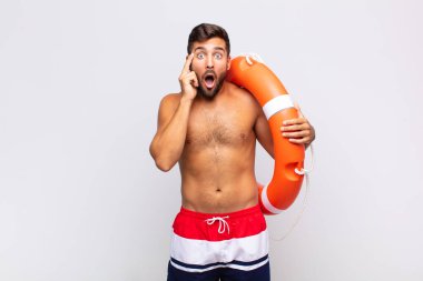 Genç adam şaşırmış, ağzı açık, şok olmuş, yeni bir düşünce, fikir ya da konseptin farkına varıyor. tatil kavramı