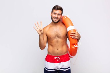 Genç adam gülümsüyor ve arkadaş canlısı görünüyor, dört ya da dört numarayı gösteriyor, eli önde, geri sayıyor. tatil kavramı