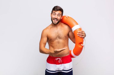 Genç adam mutlu bir şekilde gülümsüyor, mutlu hissediyor ve fotokopi uzayı içinde avucunun içi gibi bir konsept gösteriyor. tatil kavramı