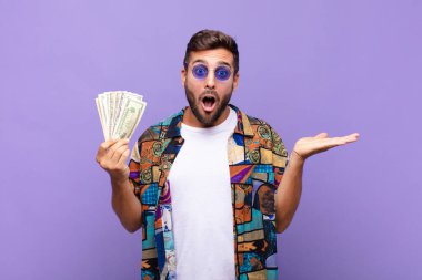 Genç adam şaşırmış ve şok olmuş görünüyor, çenesi düşmüş ve eli açık bir obje tutuyor. tatil kavramı