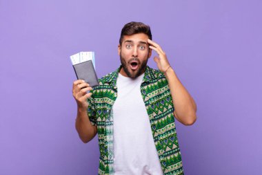 Genç adam mutlu, şaşkın ve şaşırmış görünüyor, gülümsüyor ve inanılmaz ve inanılmaz iyi haberleri fark ediyor. tatil kavramı