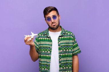 Genç adam üzgün ve mızmızlanıyor, mutsuz bir bakışla, negatif ve hayal kırıklığına uğramış bir tavırla ağlıyor. tatil kavramı