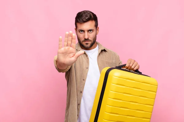 young man looking serious, stern, displeased and angry showing open palm making stop gesture. holidays concept