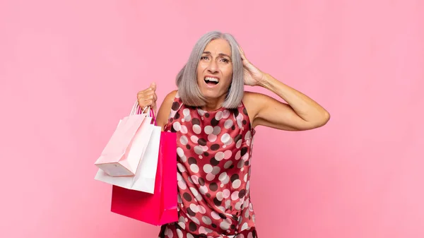中年の女性はストレスを感じ 心配し 不安や恐怖を感じ 手を頭の上に置き 買い物袋で誤ってパニックに陥る — ストック写真