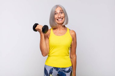 Orta yaşlı bir kadın mutlu ve hoş bir şekilde şaşırmış görünüyor. Büyülenmiş ve şok olmuş bir ifadeyle heyecanlanıyor. fitness konsepti
