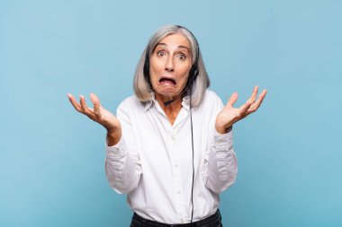 Orta yaşlı bir kadın son derece şok olmuş ve şaşırmış, endişeli ve paniklemiş, stresli ve dehşete kapılmış görünüyor. tele pazarlamacı kavramı