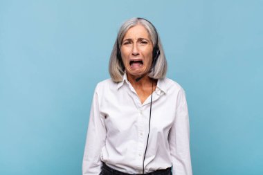 Orta yaşlı bir kadın agresif bir şekilde bağırıyor, kızgın, sinirli, öfkeli ya da sinirli görünüyor, hayır diye bağırıyor. tele pazarlamacı kavramı