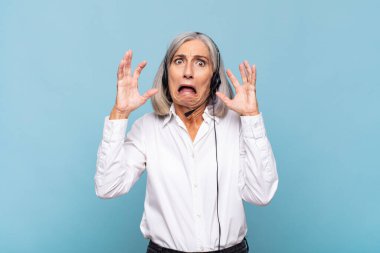 Orta yaşlı bir kadın elleri havada bağırıyor. Öfkeli, sinirli, stresli ve üzgün. tele pazarlamacı kavramı