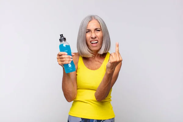 middle age woman feeling angry, annoyed, rebellious and aggressive, flipping the middle finger, fighting back. fitness concept