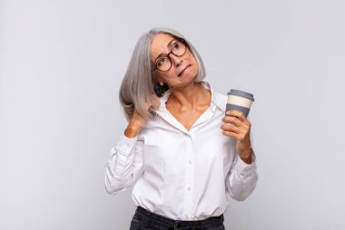 Orta yaşlı bir kadın stresli, endişeli, yorgun ve hayal kırıklığına uğramış, gömleğini çekmiş, sorunlu kahve kavramından bıkmış görünüyor.